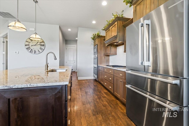 9968 Moon Shadow Ct, Middleton, ID 83644 - kitchen featuring appliances with stainless steel finishes, dark wood finished floors, light stone countertops, hanging light fixtures, and a center island with sink