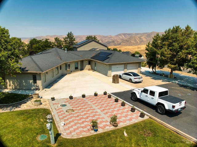 view of front facade featuring a mountain view, a garage, and solar panels