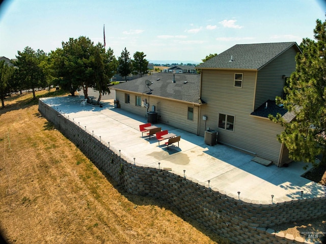 rear view of house featuring a patio, central AC, and a yard