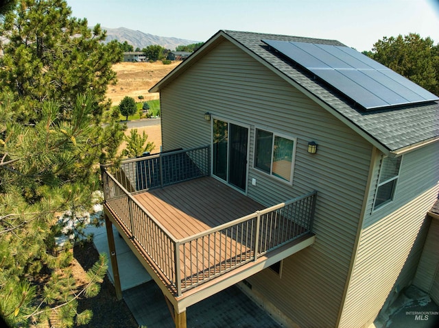 rear view of house featuring a deck with mountain view and solar panels