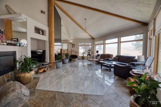 living room featuring a textured ceiling, a notable chandelier, beam ceiling, and high vaulted ceiling