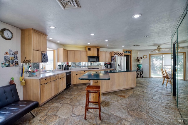 kitchen featuring a breakfast bar area, black appliances, light brown cabinets, a kitchen island, and ceiling fan