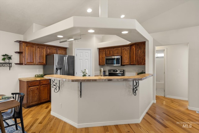 3011 S Montego Way, Nampa, ID 83686 - kitchen featuring appliances with stainless steel finishes, light wood-style flooring, light countertops, recessed lighting, and a breakfast bar