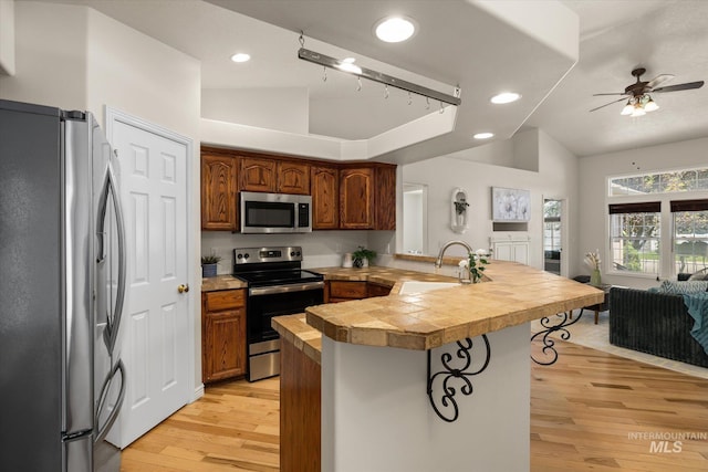 3011 S Montego Way, Nampa, ID 83686 - kitchen featuring stainless steel appliances, a sink, a peninsula, light wood finished floors, and a ceiling fan