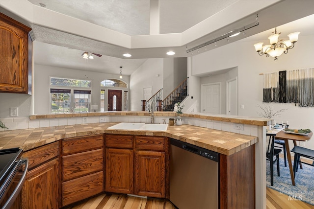 3011 S Montego Way, Nampa, ID 83686 - kitchen with stainless steel appliances, a sink, light wood-style flooring, brown cabinetry, and a peninsula