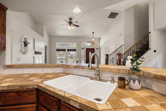 3011 S Montego Way, Nampa, ID 83686 - kitchen with a sink, a ceiling fan, open floor plan, tile countertops, and vaulted ceiling