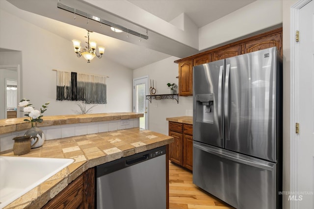 3011 S Montego Way, Nampa, ID 83686 - kitchen with stainless steel appliances, vaulted ceiling, brown cabinets, a sink, and a chandelier