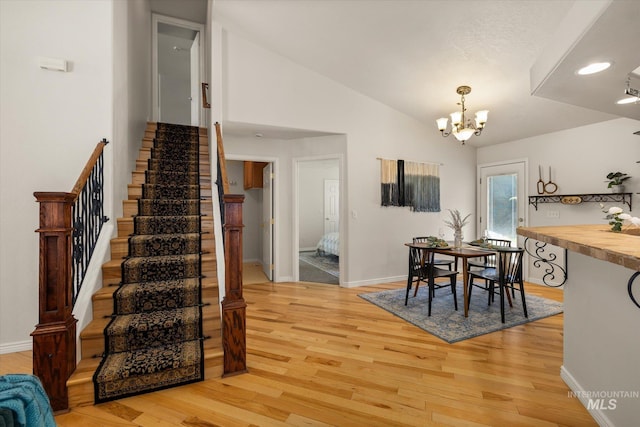 3011 S Montego Way, Nampa, ID 83686 - dining space featuring stairs, light wood finished floors, a chandelier, baseboards, and lofted ceiling