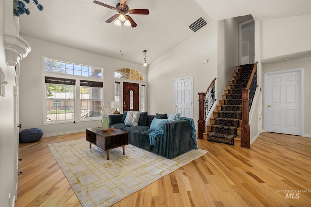 3011 S Montego Way, Nampa, ID 83686 - living room with stairs, light wood finished floors, a ceiling fan, a towering ceiling, and baseboards