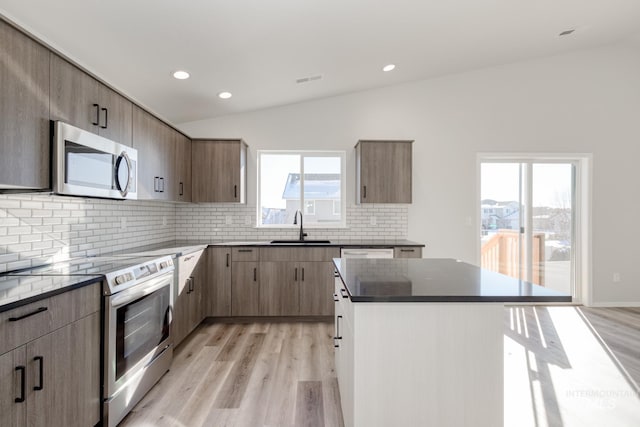 1457 W Bass River Dr, Meridian, ID 83642 - kitchen featuring stainless steel appliances, a sink, lofted ceiling, light wood-type flooring, and backsplash