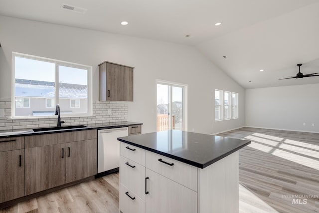 1457 W Bass River Dr, Meridian, ID 83642 - kitchen featuring dishwashing machine, a sink, dark countertops, light wood-style floors, and decorative backsplash