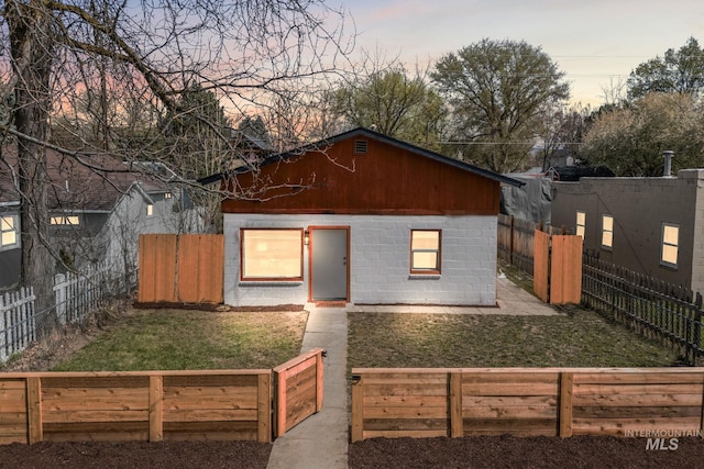 view of front of property featuring a front yard, a fenced backyard, and concrete block siding
