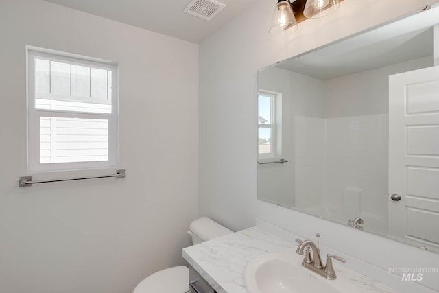 bathroom with a wealth of natural light, vanity, toilet, and a shower