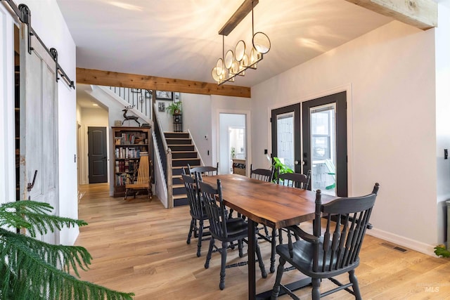dining room with visible vents, a barn door, light wood-type flooring, stairway, and french doors