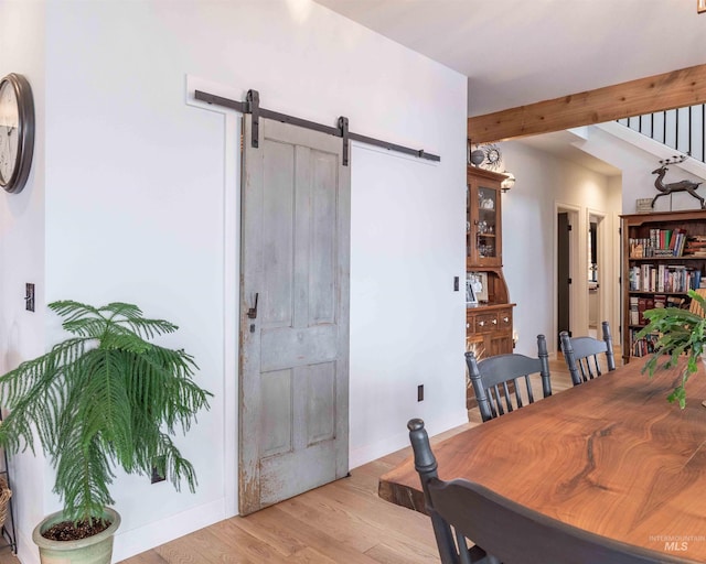 dining space with a barn door, light wood-type flooring, and baseboards
