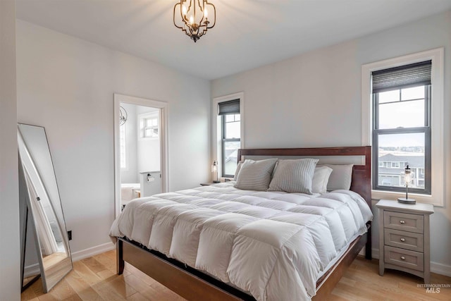 bedroom with light wood-style flooring, baseboards, and connected bathroom