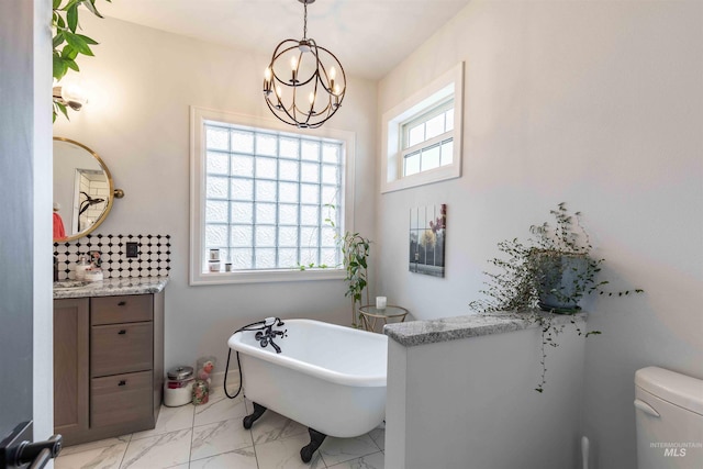 bathroom featuring a freestanding tub, vanity, a chandelier, toilet, and marble finish floor