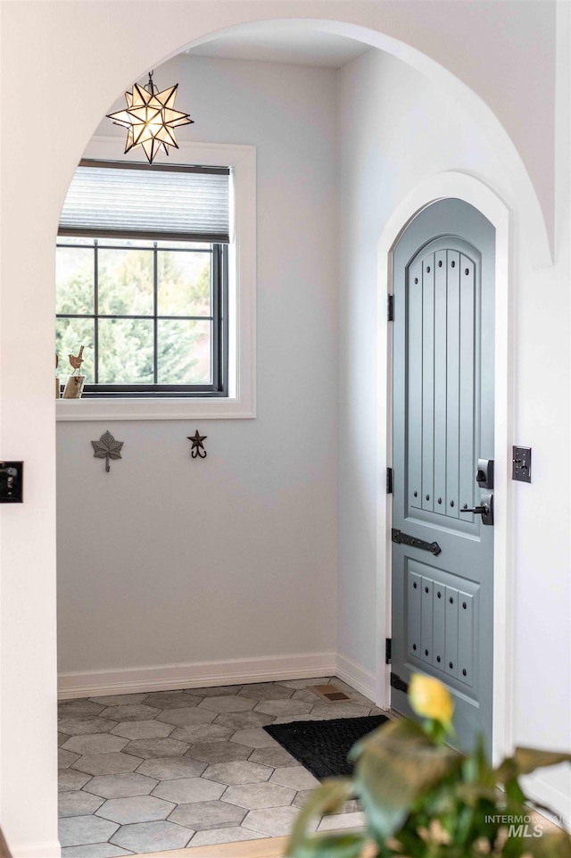 foyer entrance with arched walkways and baseboards