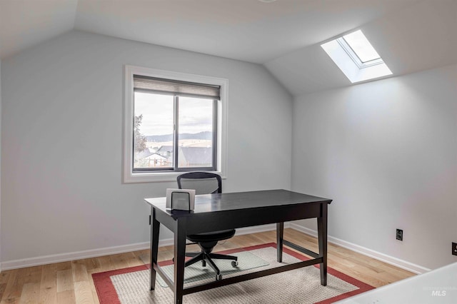 office space with baseboards, light wood finished floors, and lofted ceiling with skylight