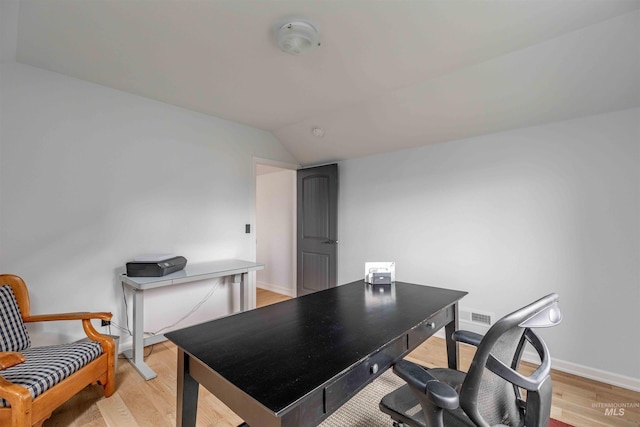 office space featuring light wood finished floors, visible vents, baseboards, and lofted ceiling