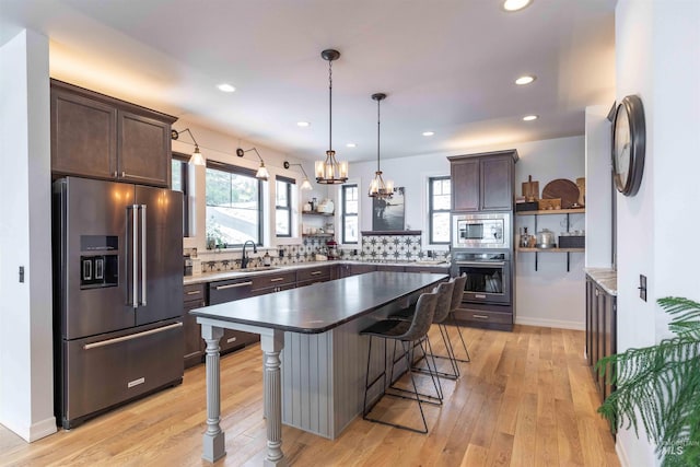 kitchen with a breakfast bar, dark brown cabinets, open shelves, and appliances with stainless steel finishes