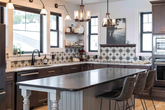 kitchen with dark brown cabinets, appliances with stainless steel finishes, a sink, and plenty of natural light