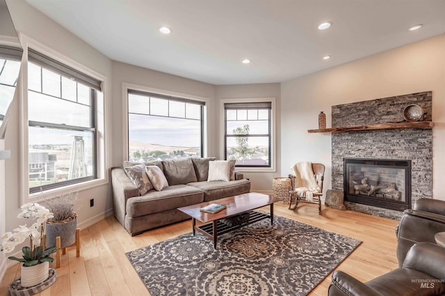 living room featuring recessed lighting, plenty of natural light, wood finished floors, and a fireplace