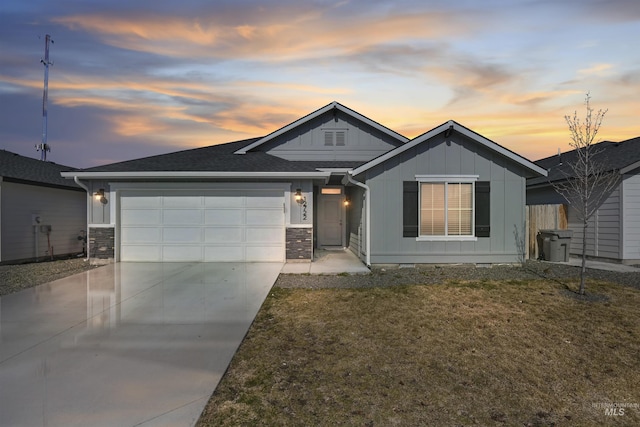 view of front of home featuring driveway, a yard, roof with shingles, board and batten siding, and an attached garage