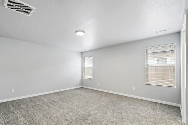 unfurnished room with carpet flooring, baseboards, and visible vents