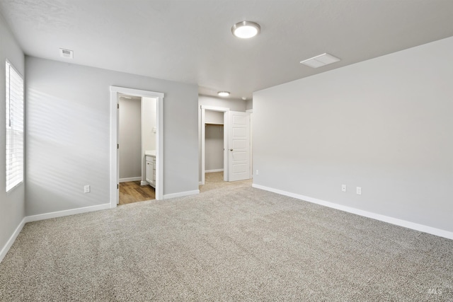 unfurnished bedroom with a spacious closet, visible vents, baseboards, and carpet floors