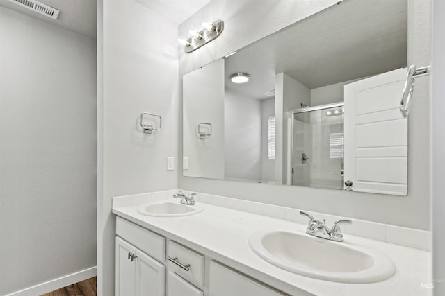 full bath with a shower stall, double vanity, visible vents, and a sink