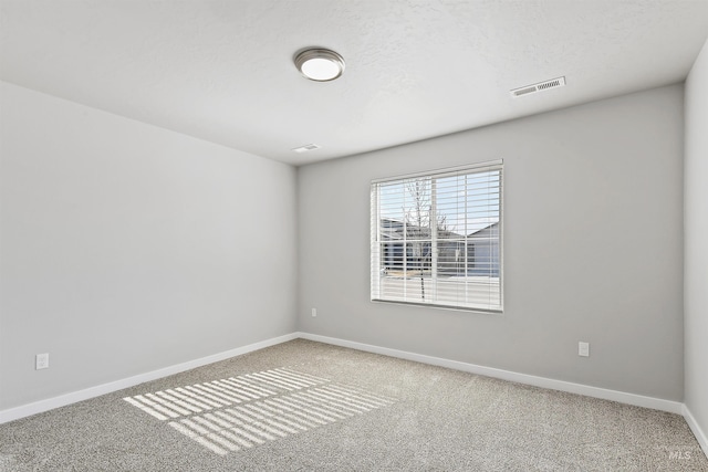 carpeted empty room with visible vents, baseboards, and a textured ceiling