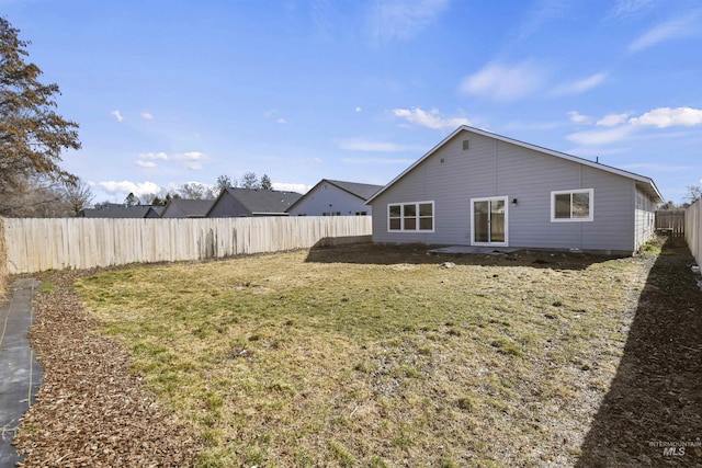 back of property with a fenced backyard and a lawn