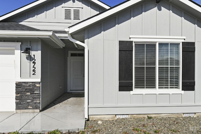 entrance to property featuring a garage, board and batten siding, and stone siding