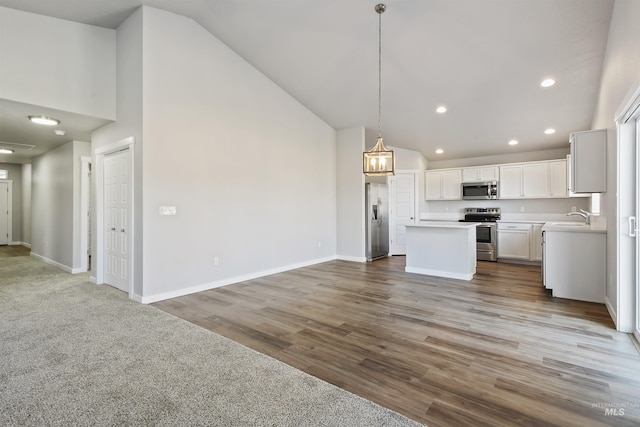 kitchen featuring baseboards, open floor plan, appliances with stainless steel finishes, and a center island