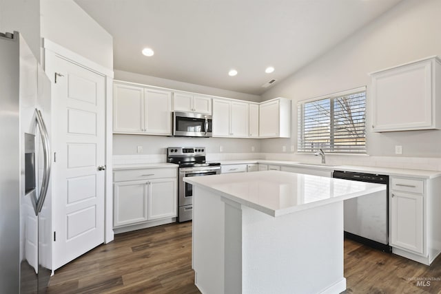 kitchen with dark wood finished floors, vaulted ceiling, stainless steel appliances, white cabinetry, and a sink