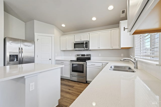 kitchen featuring dark wood finished floors, recessed lighting, a sink, stainless steel appliances, and white cabinetry