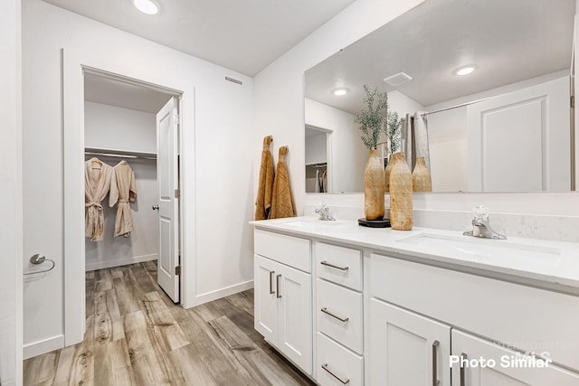 full bathroom with wood finished floors, double vanity, recessed lighting, and baseboards