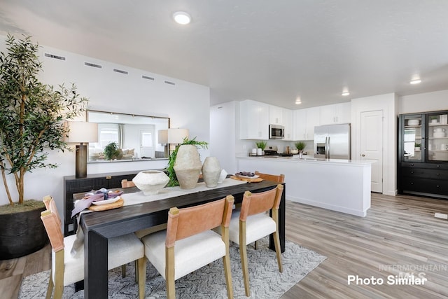 dining area with light wood finished floors and recessed lighting