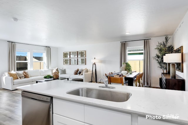 kitchen with dishwasher, open floor plan, a sink, white cabinets, and light wood-style flooring