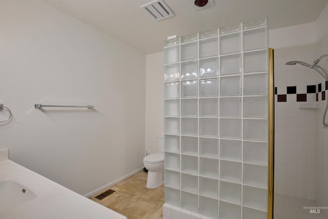 bathroom featuring vanity, tiled shower, and toilet