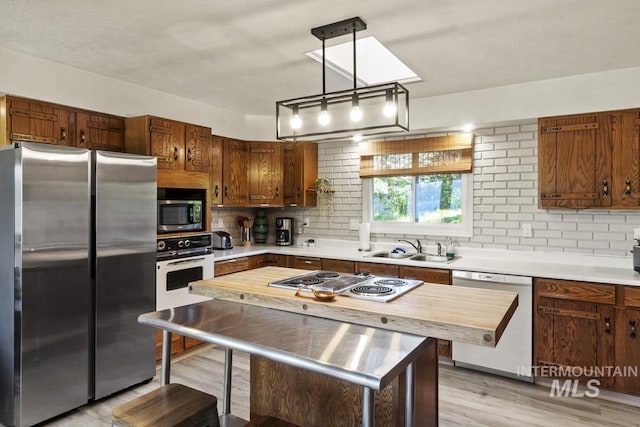 114 Par Dr, Cascade, ID 83611 - kitchen with stainless steel appliances, decorative backsplash, a sink, light wood-type flooring, and decorative light fixtures