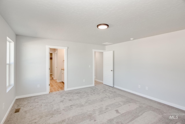 19361 James Ave, Caldwell, ID 83605 - unfurnished bedroom featuring visible vents, a textured ceiling, connected bathroom, carpet flooring, and baseboards