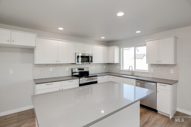 kitchen featuring a sink, light wood-style flooring, white cabinetry, and stainless steel appliances