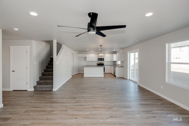 19361 James Ave, Caldwell, ID 83605 - unfurnished living room featuring a ceiling fan, recessed lighting, stairway, light wood-style floors, and baseboards