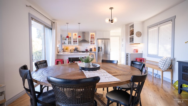 dining room with light wood-style flooring, baseboards, and a notable chandelier