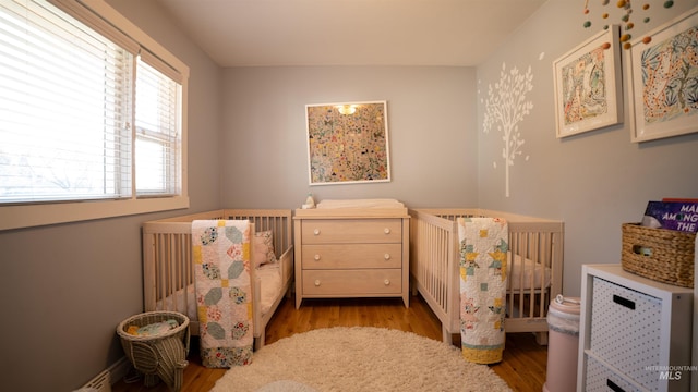 bedroom featuring a nursery area and wood finished floors