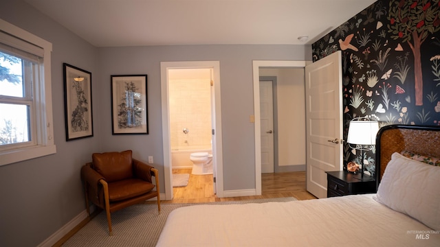 bedroom featuring baseboards, wood finished floors, and ensuite bathroom