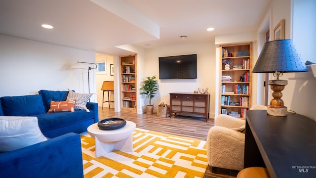 living room with baseboards, light wood finished floors, built in features, and recessed lighting