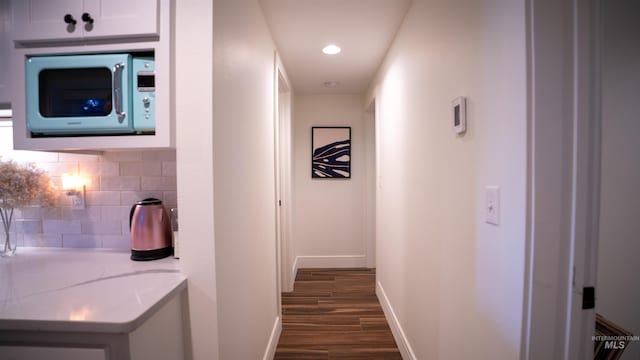 hallway featuring baseboards, dark wood finished floors, and recessed lighting